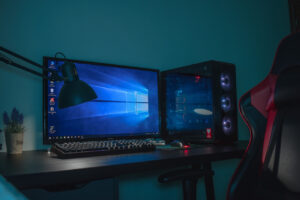 Auf einem Schreibtisch steht ein Desktop-PC, ein Gaming-Bildschirm, eine Lampe und Zubehör.