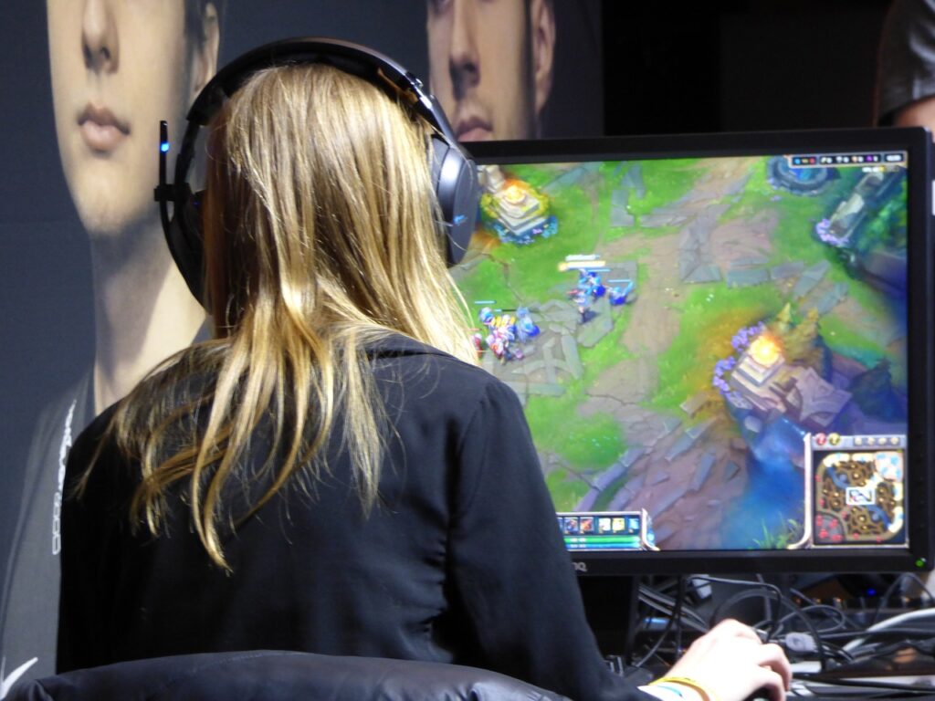 Eine Person mit langen Haaren sitzt vor einem Bildschirm und spielt League of Legends
