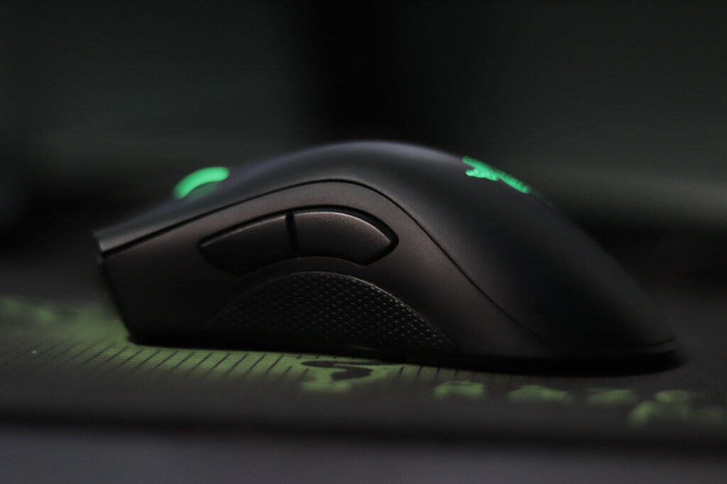Eine grün beleuchtete Maus liegt so, dass man die Zusatztasten an der linken Seite erkennen kann