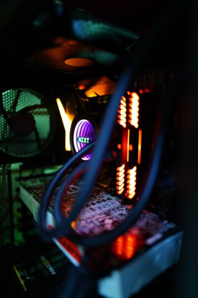 Die Hardware eines PCs ist orange, lila und grün beleuchtet. Im Hintergrund erkennt man den Gehäuselüfter