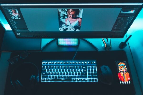 Vor einem Bildschirm liegt eine blau leuchtende Gaming Tastatur und eine Maus