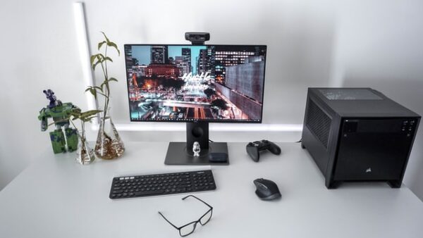 Auf einem Schreibtisch steht ein PC, Bildschirm sowie eine kabellose Tastatur und Maus