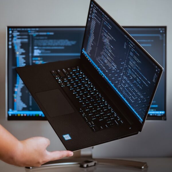 Ein Laptop wird auf einem Finger vor einem Desktop balanciert