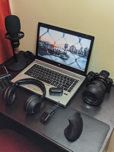 Ein Schreibtisch mit Laptop, Headset, Kamera, Mikrofon und vertikaler Maus