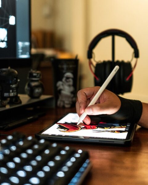 Eine Person sitzt am Schreibtisch und zeichnet auf einem Drawing-Tablet