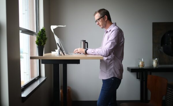 Ein Mann arbeitet an einem höhenverstellbaren Schreibtisch im Stehen